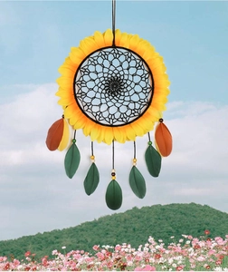 Macro detail of sunflower dream catcher with vibrant feathers against a blue sky