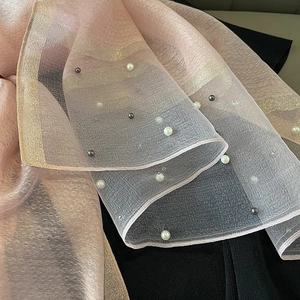 Detailed close-up of pink organza shawl featuring pearl embellishments and gold glitter trim