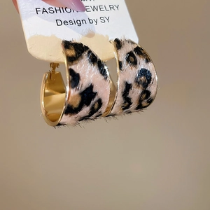 Close-up of leopard print faux fur texture and golden metal finish on C-shaped earrings