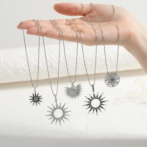 Detail of silver sun and starburst pendants with zircon inlay on model's hand