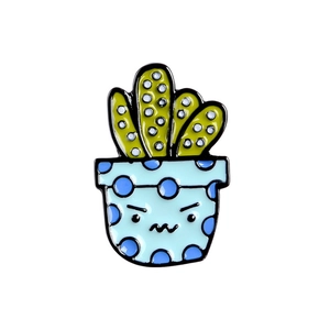 Detailed view of cartoon cactus enamel pin with blue polka dot pot on white background