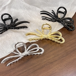 Flat lay of metal bow-shaped hair claws in black, gold, and silver finishes