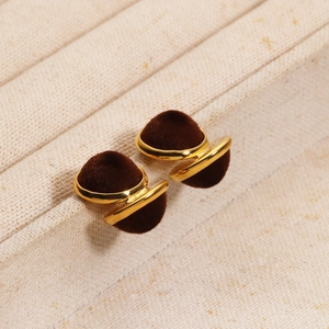 Close-up of gold-plated earrings with dark brown velvet spheres and metal accents