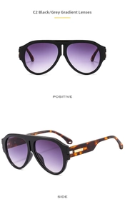 Detail view of large black frame sunglasses with tortoise temples and gradient purple lenses
