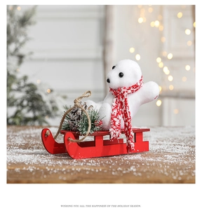 Close-up of a white flocked polar bear in a red wooden sleigh with festive pine cones
