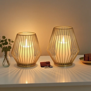 Nordic gold metal lantern candle holders with warm LED pillars on white table