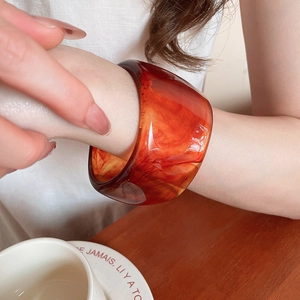 Close-up of amber acrylic resin cuff bracelet with marble texture worn by a model