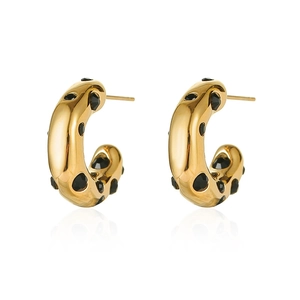Macro detail of gold-plated C-shaped earrings inlaid with black cubic zirconia stones