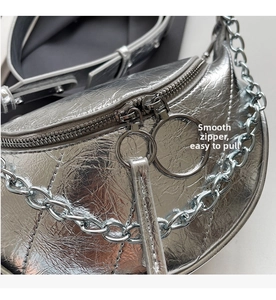 Detail of silver metallic crescent bag with dual zippers and round metal ring pullers