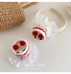 Detailed view of white lace headband with red pom-poms and daisy flowers on plain surface