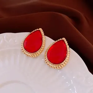 Vintage red teardrop earrings with golden twisted metal frame on an elegant background