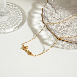 Close-up of golden stainless steel Love pendant on a crystal glass with shadows