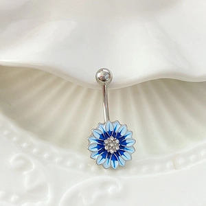 Makrofoto eines blauen Bauchnabelpiercings mit Zirkonia-Blüten auf weißer Keramik