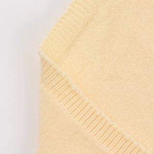 Primer plano del tejido de punto amarillo claro con detalle de borde acanalado