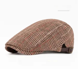 Detail of khaki plaid newsboy cap with leather adjustable strap and metal buckle