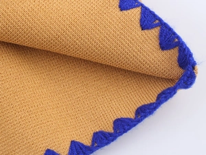 Detailed macro view of golden-brown knit fabric with vibrant royal blue crochet scalloped edges