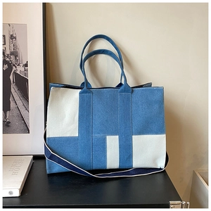 Close-up of geometric patchwork denim tote bag with wide blue fabric shoulder strap