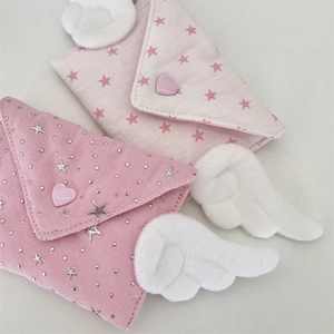 Detail of pink envelope coin purses featuring plush angel wings and star prints