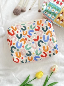 Flat lay of a white quilted cotton makeup bag with colorful abstract U-shaped patterns