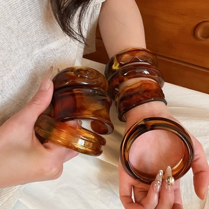Close-up of retro amber acrylic bangles with tortoiseshell patterns on model's hand