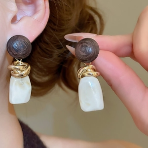 Vue détaillée de boucles d'oreilles géométriques en résine avec clous en bois et métal doré