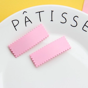 Fermagli per capelli rettangolari rosa macaron su un elegante piatto di ceramica bianca