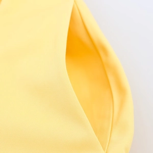 Close-up of the yellow shirt dress pocket showing high-quality stitching and woven texture