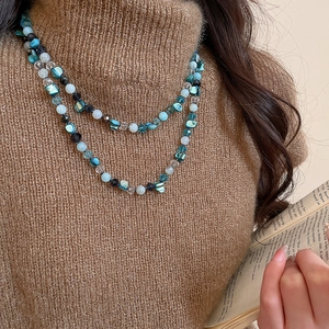 Close-up of bohemian multi-color crystal and shell beaded necklace on brown sweater