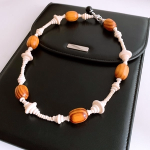 Close-up of vintage beaded necklace with oval wood beads and white spacers on black leather