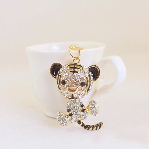 Sparkling tiger keychain with gold plating and clear crystals on a minimalist background