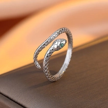 Macro shot of snake-shaped silver ring with green stone eyes and scale textures