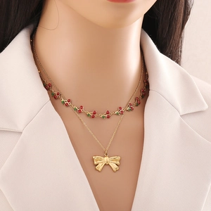 Détail d'un collier doré double épaisseur avec cerise rouge et nœud papillon sur mannequin