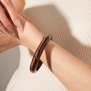 Close-up of a minimalist amber-textured resin bangle worn on a knit sleeve wrist