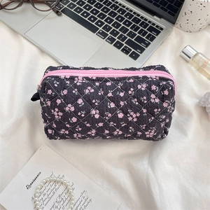 Quilted floral makeup bag with pink zipper and delicate flower pattern on black fabric