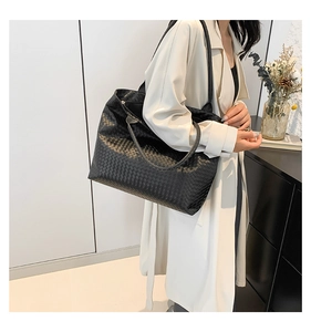 Detailed view of the black woven leather texture on a large capacity tote shoulder bag