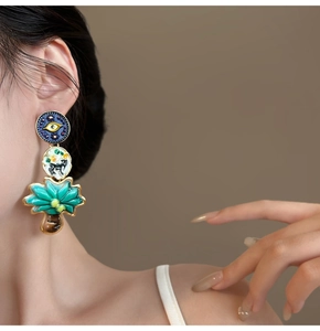 Detail of vintage layered evil eye and palm tree drop earrings on model
