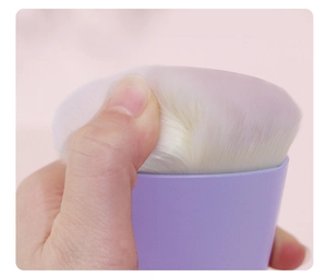 Close-up of soft white bristles on a purple makeup brush being pressed to show texture