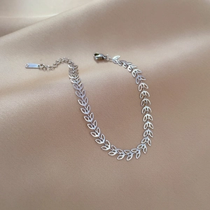 Detail of silver clover leaf link chain bracelet with lobster clasp on satin fabric