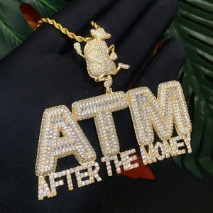 Close-up of golden ATM After The Money pendant necklace with cubic zirconia