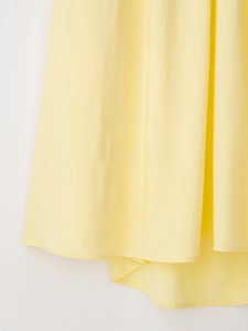 Détail du tissu fluide jaune clair et des coutures d'ourlet professionnelles de la robe