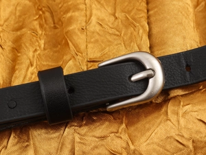 Macro-opname van zwarte leren riem met zilveren gesp op goudkleurige stof