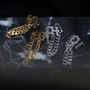 Close-up of gold and silver CH letter earrings with thick cuban link chain fringe