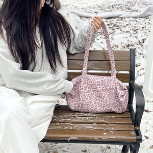 Dettaglio della borsa tote in pelle scamosciata leopardata rosa in un ambiente innevato