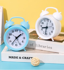 Detail of mini twin bell quartz alarm clocks in sky blue and ivory white on desk