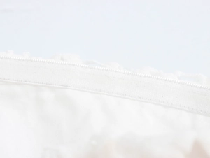 Détail d'une fermeture éclair invisible blanche et de dentelle sur une robe mi-longue
