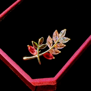Macro shot of gold branch brooch with pink gemstones on black velvet padding