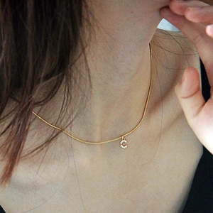 Detailed view of a gold chain necklace with a sparkling cubic zirconia letter C pendant