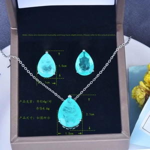 Close-up of teardrop emerald pendant and earrings jewelry set in a luxury gift box