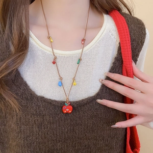 Détail du collier avec pendentif pomme rouge et breloques colorées sur cordon marron