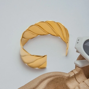 Macro shot of 18K gold plated wide cuff bracelet with modern wavy stripe textures